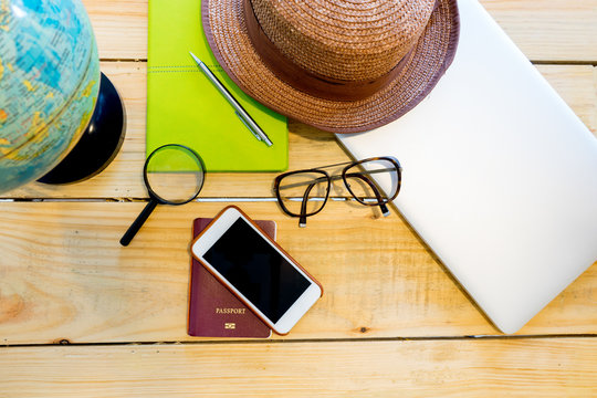 Preparation for travel, cell phone, hat, passport, laptop, notebook, glasses and map on wooden table