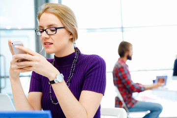 Business woman in office holding mobile phone