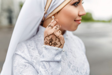 Charming muslim arabic bride in nikah wedding dress and hijab headscarf, close-up on jewelry and...