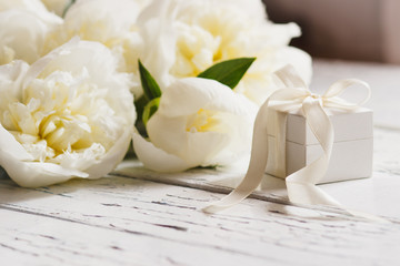 Fototapeta na wymiar Bouquet of white peonies and present box on the wooden table