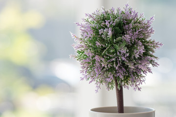 Small artificial tree and flower in a white pot without background