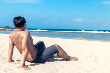 Young asian indonesian man on the beach of tropical Bali island, Indonesia.