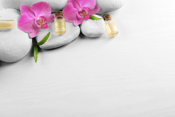Obraz na płótnie Canvas Spa stones, aroma oil with orchid flowers and bamboo leaves on white background