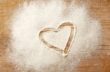 Heart drawn on flour on wooden background
