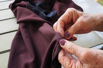 Old woman hands sewing cloth outdoors