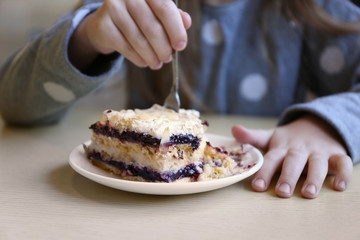 Little girl eating tasty cake, close up view