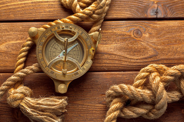 Compass and rope on wooden table. close up