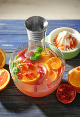 Decanter of fresh cocktail with pomegranate and orange on table