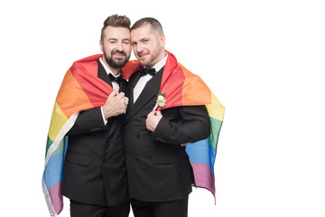 young homosexual wedding couple embracing with lgbt flag isolated on white