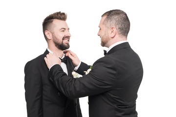 Happy man fixing bow tie of his groom isolated on white
