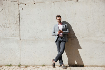Portrait of a happy man in jacket holding mobile phone