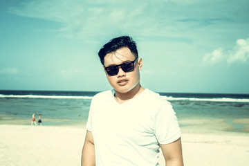 Young asian indonesian man on the beach of tropical Bali island, Indonesia.