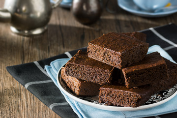 Pile of Chocolate Brownies with Hot Tea on Wooden Kitchen Table