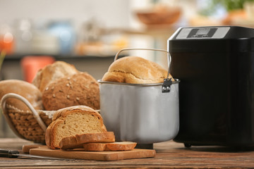 Tasty sliced loaf and bread machine on table
