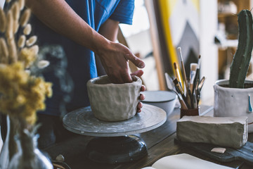 Male artisan in his workshop carefully molds sculpture with dirty hands, puts in experience and...