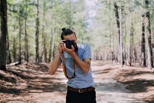 Millennial nomad hipster photographer and adventurer explores forest trails and passes, makes photo of his girlfriend on vintage analog camera