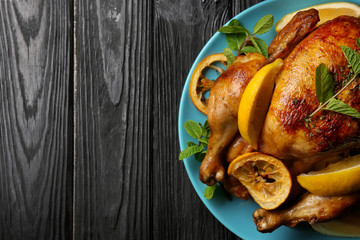 Homemade baked chicken with lemon and mint on wooden background