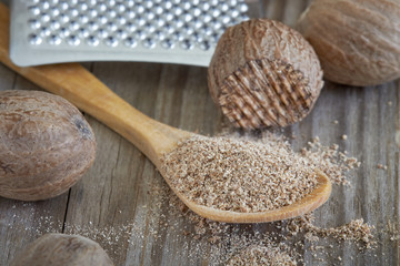 Group of nutmeg seeds with nutmeg powder in wooden spoon  - obrazy, fototapety, plakaty