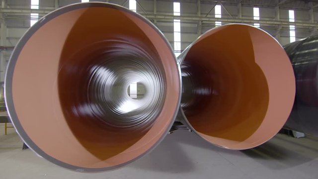 Warehouse with big diameter pipes stacked on the floor. Pipe-rolling plant.