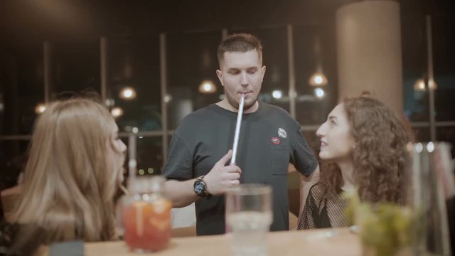 Young man smokes a hookah in the presence of girls