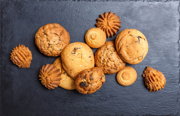 Assorted cookies with chocolate chip, oatmeal raisin on stone slate background on wooden background close up. Homemade baking. Top view, flat lay