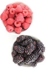 fresh blackberry and red raspberry fruits in small white bowls