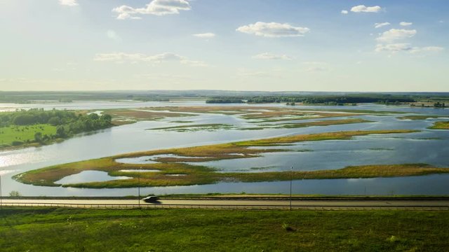 A large number of trucks and cars driving on the road along the lake. Timelapse