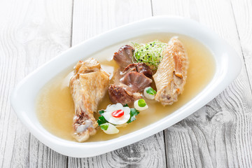 Homemade jelly chicken decorated with greens and eggs on plate on wooden background close up. Cold Meat Dishes