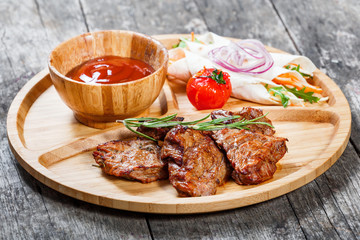 Grilled beef and vegetables with fresh salad and bbq sauce on cutting board on wooden background close up. Hot Meat Dishes. Top view