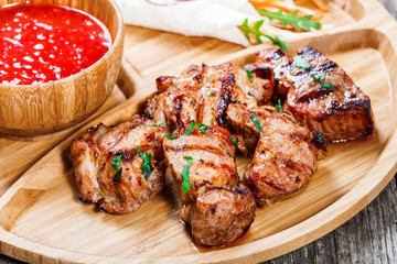 Grilled pork and vegetables with fresh salad and bbq sauce on cutting board on wooden background close up. Hot Meat Dishes. Top view