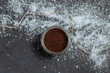brown scrub into a glass jar with jute thread loose shiny artificial snow on a dark grey black background copyspace close-up