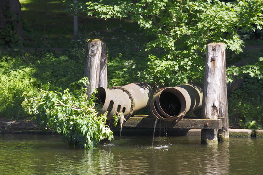 Alte Abwasserrohe auf Holzgestell an einem Gewässer
