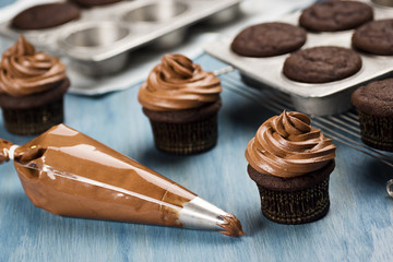 Decorating Chocolate Cupcakes with Frosting in Pastry Bag