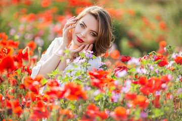 Naklejka premium Pretty woman in field of red poppy flowers, spring time