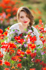 Pretty woman in field of red poppy flowers, spring time