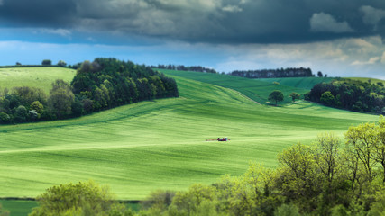 Fototapeta na wymiar Agricultural Machine Spraying Pesticides on Green Wheat Hills