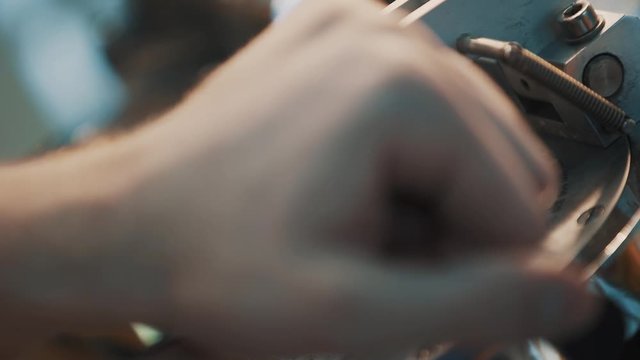 Male hands fixes glass lens in precise metal machine with circular markings, putting rins inside holes, close up