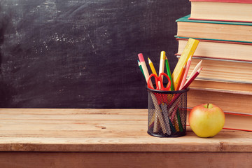 Back to school background with books, pencils and apple over chalkboard