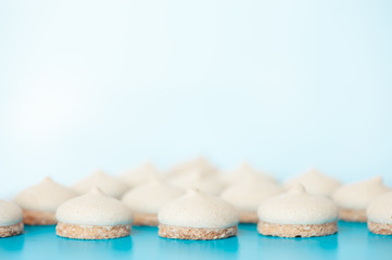 Small white cakes on a blue background. In the distance they are blurred.