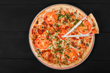 Pizza with chicken, tomatoes, mushrooms, greens and cheese on dark wooden background. Homemade pizza. Top view