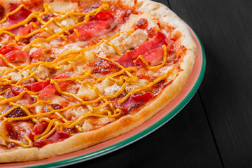 Pizza with chicken, ham, salami, pineapple and mustard on dark wooden background. Homemade pizza