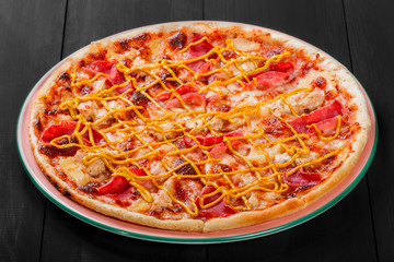 Pizza with chicken, ham, salami, pineapple and mustard on dark wooden background. Homemade pizza