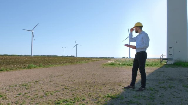 The engineer stands on the background of the windmills.