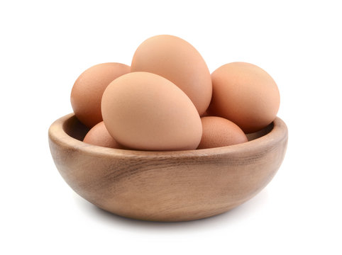 Chicken eggs in a wooden bowl isolated