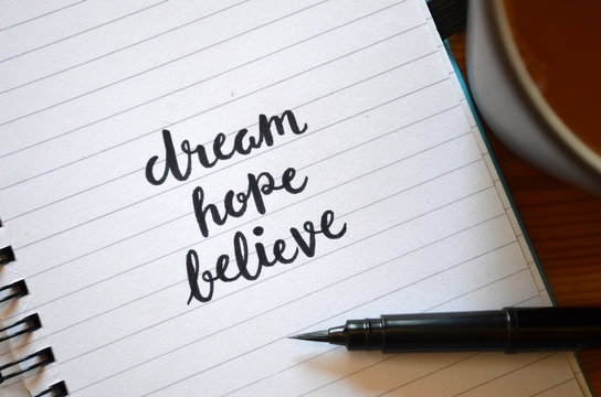 DREAM HOPE BELIEVE motivational quote written in notebook