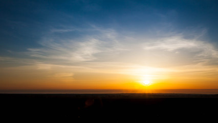 Natural Sunset Sunrise Over Field Or Meadow. Bright Dramatic Sky And Dark Ground. Countryside Landscape Under Scenic Colorful Sky At Sunset Dawn Sunrise. Sun Over Skyline, Horizon. Warm Colours.