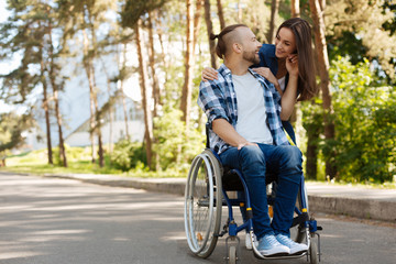 Positive delighted invalid man touching hair of his girlfriend