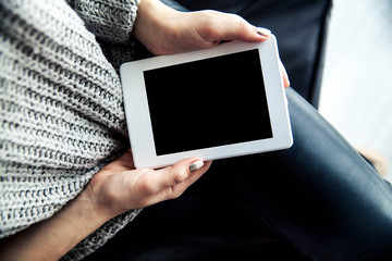 A girl holding a tablet in hands, reader with a nice manicure. Leather trousers, ugg boots. Fashion, style, learning, modern, recreation