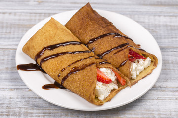 Pancakes with cottage cheese, strawberry, chocolate and on the wooden table