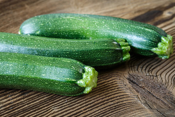 Fresh zucchini on cutting board, on wooden background.